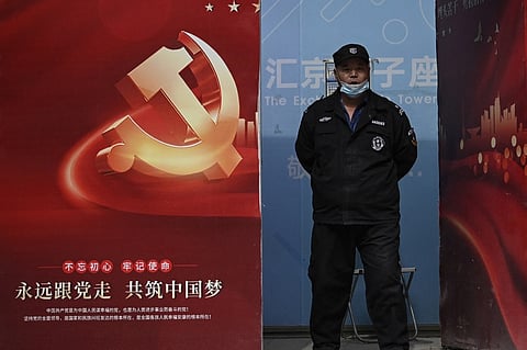 A security guard stands by a propaganda poster welcoming the 20th Communist Party Congress, in Beijing on 12 October 2022. (Photo by JADE GAO / AFP)