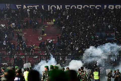 This picture taken on 1 October 2022 shows security personnel (lower) on the pitch after a football match between Arema FC and Persebaya Surabaya at Kanjuruhan stadium in Malang, East Java. At least 127 people died at a football stadium in Indonesia late on 1 October when fans invaded the pitch and police responded with tear gas, triggering a stampede, officials said. (Photo by AFP)
