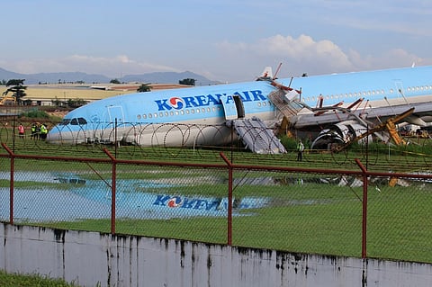 The plane of Korean Air flight KE631 lies with its belly on the runway at the airport in Cebu City on 24 October 2022, after it overshot the runway late October 23 while landing in bad weather. (Photo by ALAN TANGCAWAN / AFP)