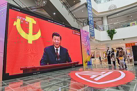 People watch a live broadcast of China's President Xi Jinping speaking during the introduction of the Communist Party of China's Politburo Standing Committee, on a screen at a shopping mall in Qingzhou in China's eastern Shandong province on 23 October 2022. (Photo by AFP)