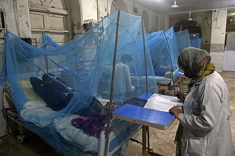Patients suffering from dengue fever rest under mosquito nets at a hospital in Karachi on 4 October 2022. (Photo by ASIF HASSAN / AFP)