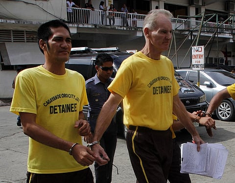 This file photo taken on June 16, 2015 shows Peter Scully of Australia (R), accused of raping and trafficking two girls in the Philippines, leaving the court handcuffed to another inmate (L) after his arraignment in Cagayan de Oro City, on the southern Philippine island of Mindanao. - Scully has been sentenced to 129 years in a Philippine jail as part of a child sexual abuse case involving victims as young as 18 months, a prosecutor said on November 9, 2022. (Photo by AFP)