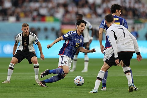 Japan's midfielder #15 Daichi Kamada runs with the ball past Germany's midfielder #07 Kai Havertz during the Qatar 2022 World Cup Group E football match between Germany and Japan at the Khalifa International Stadium in Doha on November 23, 2022. (Photo by Adrian DENNIS / AFP)