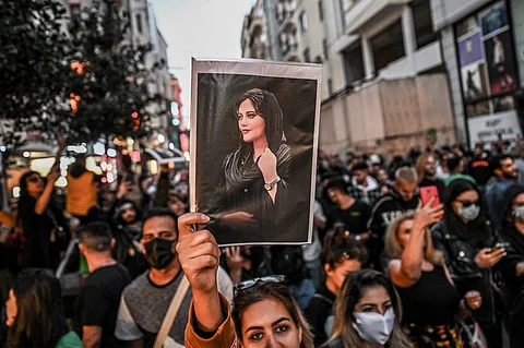 A protester holds a portrait of Mahsa Amini during a demonstration in support of Amini, a young Iranian woman who died after being arrested in Tehran by the Islamic Republic's morality police, on Istiklal avenue in Istanbul on 20 September 2022. (Photo by OZAN KOSE / AFP)