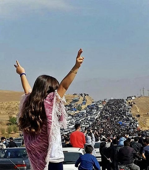 This UGC image posted on Twitter reportedly on 26 October 2022 shows an unveiled woman standing on top of a vehicle as thousands make their way towards Aichi cemetery in Saqez, Mahsa Amini's home town in the western Iranian province of Kurdistan, to mark 40 days since her death, defying heightened security measures as part of a bloody crackdown on women-led protests. (Photo by UGC / AFP)