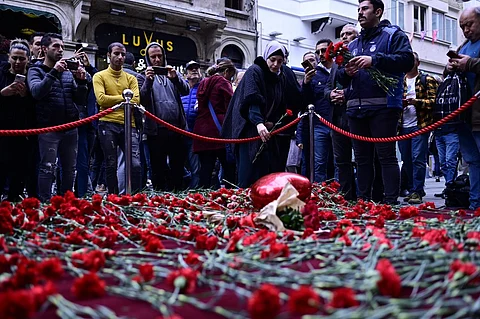 People lay flowers at a makeshift memorial for the victims of the 13 November explosion at the busy shopping street of Istiklal in Istanbul on 14 November 2022. (Photo by YASIN AKGUL / AFP)
