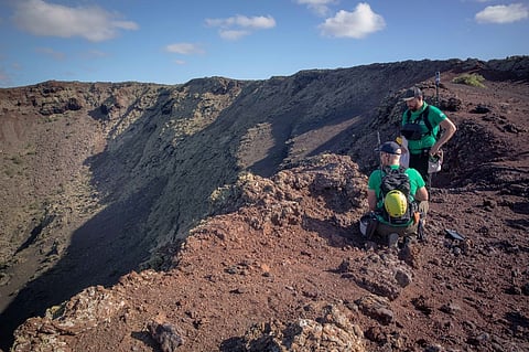 German astronaut Alexander Gerst (right) work on the summit of an ancient volcano during a training program to learn how to explore the Moon and Mars in the Timanfaya National Park in the Canary island of Lanzarote on 10 November 2022. (Photo by DESIREE MARTIN / AFP)