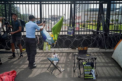 A parliament building's security man takes a photograph of protest materials as activists hold a protest against the new criminal code outside Parliament in Jakarta on 6 December 2022. Photo by BAY ISMOYO / AFP