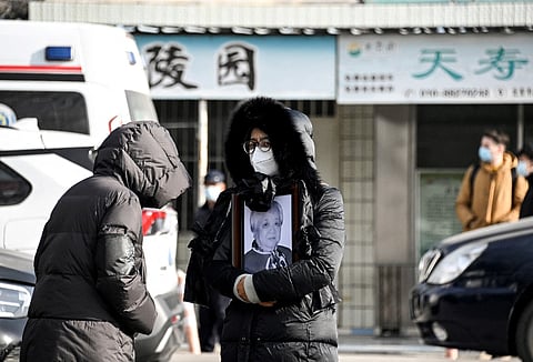 A woman holds a picture frame of a loved one at a crematorium in Beijing on December 20, 2022. - Workers at Beijing crematoriums said on December 16 they are overwhelmed as China faces a surge in Covid cases that authorities warn could hit its underdeveloped rural hinterland during upcoming public holidays. Photo by Noel Celis / AFP