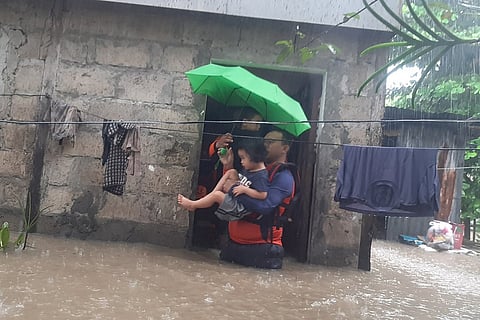 This handout photo taken on December 25, 2022 and received on December 26 from the Philippine Coast Guard shows rescuers evacuating a child from a flooded area in Ozamiz City, Misamis Occidental. - Two people were killed and nearly 46,000 others fled their homes as Christmas Day floods dampened the mainly Catholic Philippines's most important holiday, civil defence officials said on December 26. Photo by Handout / Philippine Coast Guard (PCG) / AFP