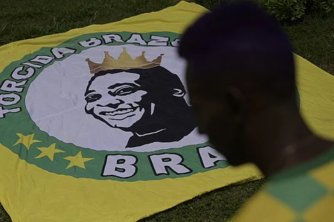 A fan pays homage to Pele in front of a replica of the house where he was born and which was built according to the memories of his mother, Celeste Arantes, in Tres Coracoes, state of Minas Gerais, Brazil, on 30 December. Photo by DOUGLAS MAGNO / AFP