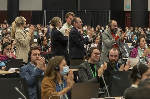Norwegian Minister of Climate and the Enviroment Espen Barth Eide (center) and several other participants applaud at a plenary meeting of the United Nations Biodiversity Conference in Montreal, Canada, on 19 December 2022. (Photo by LARS HAGBERG / AFP)