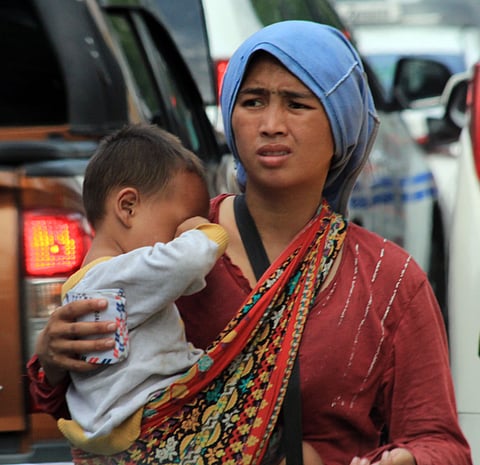 (FILE PHOTO) WITH a baby in tow, this Badjao woman begs for alms on roadsides unmindful of the risks.