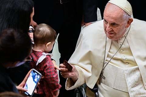 Pope Francis hands a child a rosary during an audience to the Movement of Christian Workers. The Holy Father’s writings are being translated to Pilipino.