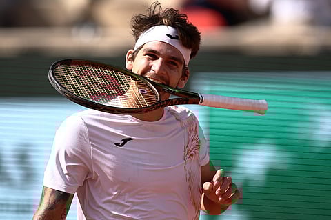 Brazil's Thiago Seyboth Wild bites his racket during his match against Russia's Daniil Medvedev during their men's singles match on day three of the Roland-Garros Open tennis tournament at the Court Philippe-Chatrier in Paris on 30 May 2023. (Photo by Anne-Christine POUJOULAT / AFP)