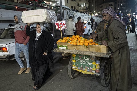 FILE PHOTO: People walk past a pedlar selling tangerines along a street in the Azhar district of Egypt's capital Cairo. (Photo by Khaled DESOUKI / AFP)