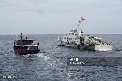 FILE PHOTO: This photo taken on 22 August 2023 from the deck of Philippine coast guard ship BRP Cabra shows a Chinese coast guard ship (R) shadowing a civilian boat chartered by the Philippine navy to deliver supplies to Philippine navy ship BRP Sierra Madre in the disputed South China Sea. (Photo by Ted ALJIBE / AFP)