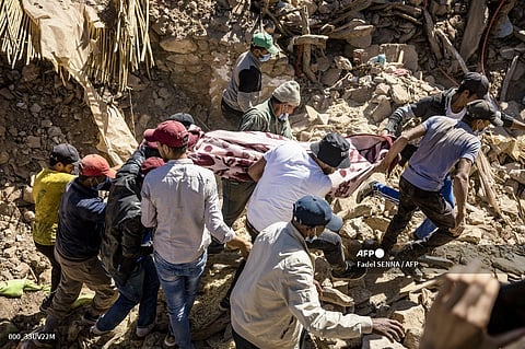 Volunteers recover a body from the rubble of collapsed houses in Tafeghaghte, 60 kilometres (37 miles) southwest of Marrakesh, on September 10, 2023, two days after a devastating 6.8-magnitude earthquake struck the country. Moroccans on September 10 mourned the victims of a devastating earthquake that killed more than 2,000 people as rescue teams raced to find survivors trapped under the rubble of flattened villages. (Photo by Fadel SENNA / AFP)