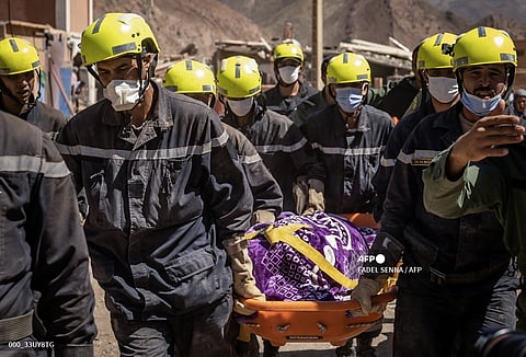 Moroccan rescuers carry a body out of the rubble in Talat N'Yacoub village of al-Haouz province in earthquake-hit Morocco on September 11, 2023. Moroccan rescuers supported by newly-arrived foreign teams on September 11 faced an intensifying race against time to dig out any survivors from the rubble of mountain villages, on the third day after the country's strongest-ever earthquake. (Photo by FADEL SENNA / AFP)