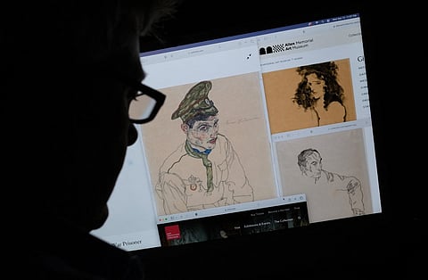 This photo illustration created in Los Angeles, California, on 13 September 2023, shows a person looking on a computer screen at artwork by Austrian Expressionist Egon Schiele entitled "Russian War Prisoner" (L), "Portrait of a Man" (R) and "Girl With Black Hair" (top), which were seized by investigators after the Manhattan district attorneys office issued warrants. US authorities seized three artworks sought by the heirs of a Jewish art collector who died in the Holocaust, officials said on 14 September 2023. (Photo by Chris DELMAS / AFP)
