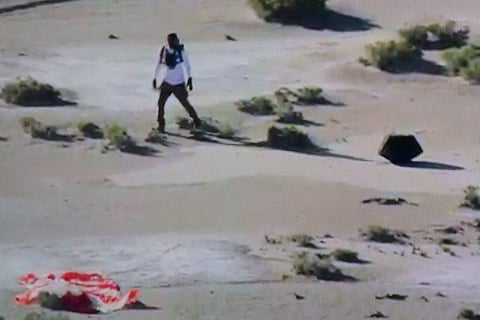This shot off a NASA live feed shows a NASA safety team member approaching the Osiris-Rex asteroid sample's return craft sitting in the Utah desert at Dugway, Utah, on 24 September 2023.(Photo by Handout / NASA / AFP)