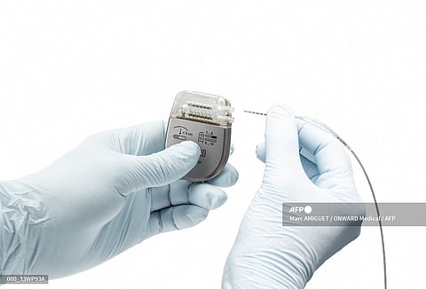 This April 12, 2020, image courtesy of ONWARD Medical shows the insertion of the lead electrodes into the Neurostimulator (IPG). Photo by Marc AMIGUET / ONWARD Medical / AFP