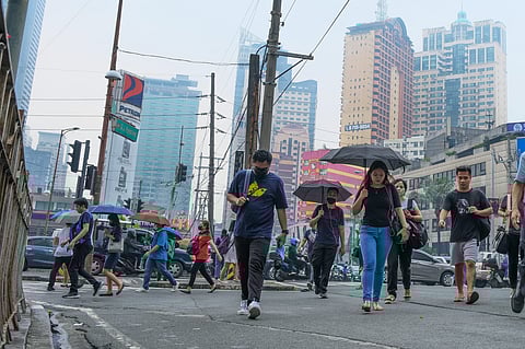 PEOPLE walk along Makati Avenue with the haze-shrouded towers of the premier commercial and business district as backdrop. To reduce the health risks posed by the pollution smog, the majority of local governments in Metro Manila suspended classes at all levels in public and private schools. | PHOTOGRAPH BY KING RODRIGUEZ FOR THE DAILY TRIBUNE