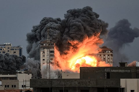 (FILE) EDITORS NOTE: Graphic content / People standing on a rooftop watch as a ball of fire and smoke rises above a building in Gaza City on October 7, 2023 during an Israeli air strike. At least 70 people were reported killed in Israel, while Gaza authorities released a death toll of 198 in the bloodiest escalation in the wider conflict since May 2021, with hundreds more wounded on both sides. (Photo by MAHMUD HAMS / AFP)