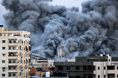 A plume of smoke rises above buildings in Gaza City on 7 October 2023 during an Israeli air strike. At least 70 people were reported killed in Israel, while Gaza authorities released a death toll of 198 in the bloodiest escalation in the wider conflict since May 2021. (Photo by MAHMUD HAMS / AFP)
