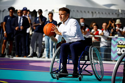 French President Emmanuel Macron plays basketball with Paralympic athletes during the Paralympic Day at Place de la Republique, in Paris, on 8 October 2023. (Photo by SARAH MEYSSONNIER / POOL / AFP)