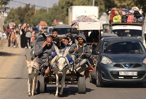 Riding a donkey drawn cart as family along with hundreds of other Palestinian carrying their belongings flee following the Israeli army's warning to leave their homes and move south before an expected ground offensive, in Gaza City on 13 October 2023. Palestinians carried belongings through the rubble-strewn streets of Gaza City on 13 October, in search of refuge as Israel's army warned residents to flee immediately before an expected ground offensive in retaliation against Hamas for the deadliest attack in Israeli history. (Photo by MAHMUD HAMS / AFP)