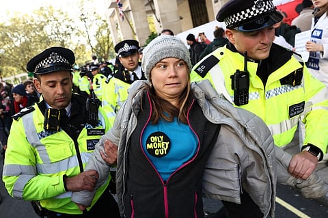 Swedish climate activist Greta Thunberg reacts as she is taken towards a police van after being arrested outside the InterContinental London Park Lane during the "Oily Money Out" demonstration organised by Fossil Free London and Greenpeace on the sidelines of the opening day of the Energy Intelligence Forum 2023 in London on October 17, 2023. (Photo by HENRY NICHOLLS / AFP)