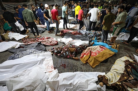 EDITORS NOTE: Graphic content / People gather around bodies of Palestinians killed after a blast ripped through the Ahli Arab hospital in central Gaza after they were transported to Al-Shifa hospital, on October 17, 2023. Israel and Palestinians traded blame for the incident, which an "outraged and deeply saddened" US President Joe Biden denounced while en route to the Middle East. (Photo by Dawood NEMER / AFP)