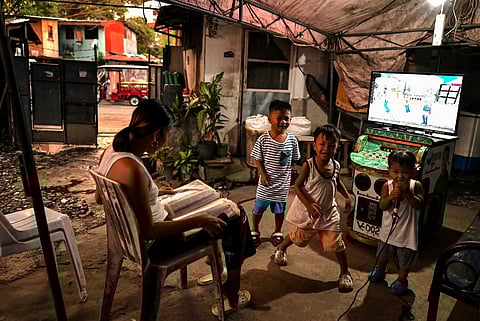 FILE PHOTO: This photo taken on 17 October 2023 shows a woman singing a tune from a karaoke machine during a birthday celebration in Manila. (Photo by JAM STA ROSA / AFP)