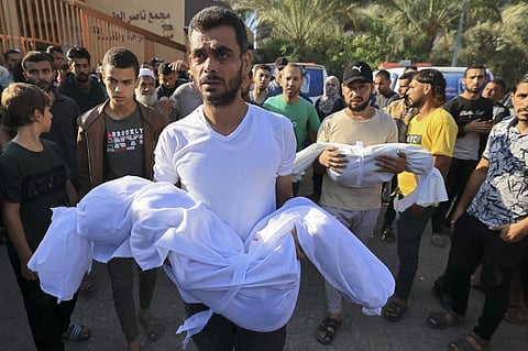 The fathers of children from the al-Majaida family killed when an Israeli air strike hit their home carry their bodies during their funeral in Khan Yunis on the southern Gaza Strip, on October 19, 2023. (Photo by Mahmud HAMS / AFP)