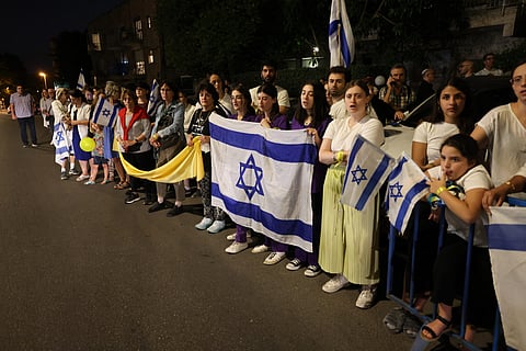 Demonstrators holding the Israeli flag and a yellow ribbon rally calling for the release of Israeli hostages held by the Palestinian Hamas militants since the 7 October attack, outside the Israeli President's residence in Jerusalem on 22 October 2023, amid the ongoing battles between Israel and the Palestinian group Hamas. (Photo by AHMAD GHARABLI / AFP)