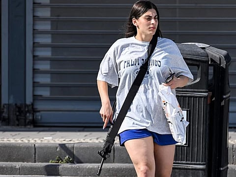 Open carry Israeli adult civilians in communities bordering Gaza have been allowed to tote weapons, like this woman seen exiting a convenience store armed with an M16 rifle in Sderot, southern Israel this week. Arming civilians is not a problem in Israel in view of its mandatory military training for all able-bodied men and women. | Getty Images/AGENCE FRANCE-PRESSE