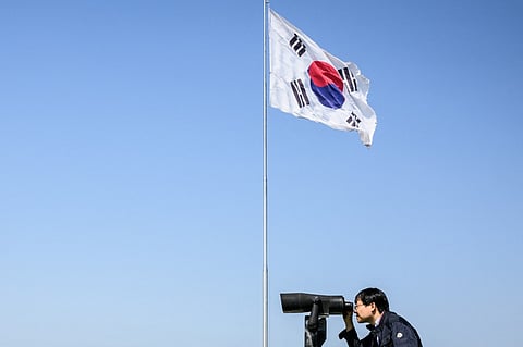 FILE: A visitor uses binoculars to look towards the North Korean side of the Demilitarized Zone (DMZ) from the Odusan Unification Tower in Paju on 12 May 2022. (Photo by ANTHONY WALLACE / AFP)
