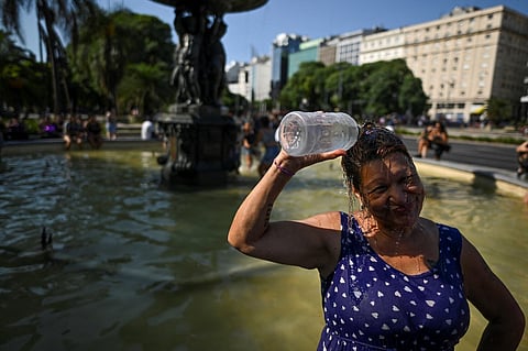 A woman cool off in a fountain on 9 de Julio avenue in Buenos Aires on March 8, 2023. Argentina is enduring this year's most torrid summer ever reported, with record temperatures and a lack of rainfall. This unprecedented weather scenario is damaging agriculture and keeping the country under red alert, according to reports from the National Meteorological Service (SMN). (Photo by Luis ROBAYO / AFP)