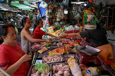 FILE PHOTO: A woman gives change to a customer at a market in Manila on 5 October 2023. (Photo by JAM STA ROSA / AFP)