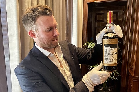 A member of staff shows a bottle of the Macallan Valerio Adami 60 Year Old 42.8 abv 1926, the world's most valuable whisky estimated between 750,000 - 1,200,000 £ (860,800 - 1,377,300 ), during a photocall at the auction house Sotheby's in London, on October 19, 2023. The auction will take place in London on November 18, 2023. (Photo by Mathilde BELLENGER / AFP)