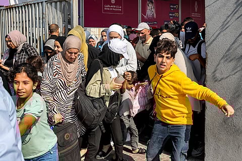 People walk through a gate to enter the Rafah border crossing to Egypt in the southern Gaza Strip on November 1, 2023. Photo by Mohammed ABED / AFP