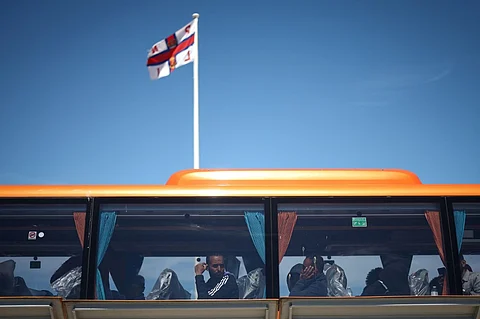 FILE PHOTO: Migrants look out from the window of a bus that will take them for processing, in Dungeness, on the southeast coast of England, on 16 August 2023 after being pick up at sea by a Royal National Lifeboat Institution (RNLI) lifeboat while crossing the English Channel from France. (Photo by HENRY NICHOLLS / AFP)