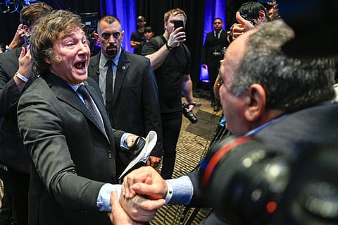 Argentine presidential candidate for the La Libertad Avanza alliance Javier Milei (L) celebrates with supporters after winning the presidential election runoff at his party headquarters in Buenos Aires on 19 November 2023. (Photo by LUIS ROBAYO / AFP)
