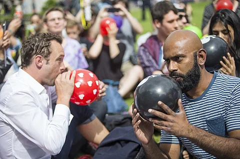 FILE PHOTO: Dozens of protesters stage a mass inhalation of nitrous oxide, commonly known as laughing gas, outside the Houses of Parliament in central London on 1 August 2015. (Photo by JACK TAYLOR / AFP)