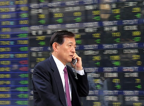 FILE PHOTO: A businessman passes before a share prices board in Tokyo. (Photo by YOSHIKAZU TSUNO / AFP)