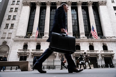 FILE PHOTO: People walk past the New York Stock Exchange (NYSE) in New York City. (Photo by SPENCER PLATT / GETTY IMAGES NORTH AMERICA / Getty Images via AFP)