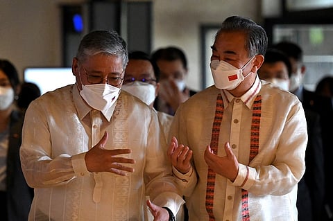 FILE PHOTO: Philippine Foreign Affairs Secretary Enrique Manalo (L) and China's Foreign Minister Wang Yi (R) interact as they arrive for bilateral talks at the Department of Foreign Affairs in Manila on 6 July 2022. (Photo by JAM STA ROSA / POOL / AFP)