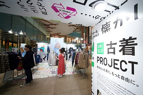 This picture taken on 17 October 2023 shows customers browsing through items sold as part of the Uniqlo Pre-owned Clothes Project at the brand's Harajuku store in Tokyo. Uniqlo's recent second-hand pop-up store in Tokyo was a first for the Japanese casual clothing giant but also a sign that local consumers' aversion to used garments may finally be fading. (Photo by Kazuhiro NOGI / AFP)