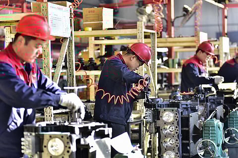 FILE PHOTO: Employees work on engines at a factory in Qingzhou, in China's eastern Shandong province on 30 November 2023. (Photo by AFP) / China OUT